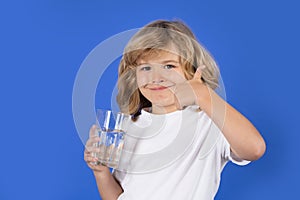 Kid drinking water, isolated on studio background. Cute blonde child boy enjoy pure fresh mineral water. Thirsty kid