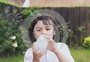 Kid drinking water, Thirsty boy holding a bottle of water, Child drinking water while playing in the garden, World Children day,