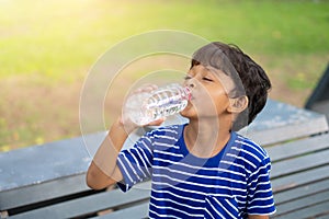 Kid drinking water from a transparent plastic bottle