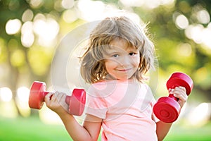 Kid dumbbells exercising. Sporty child with dumbbell outdoor. Kids sport. Boy workout in park. Kids active healthy