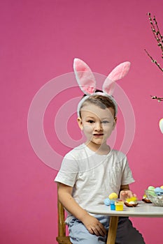 Kid dyeing Easter eggs. Children in bunny ears dye colorful egg for Easter hunt. Home decoration for spring holiday