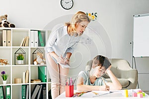 Kid with dyslexia drawing with pencil and child psychologist