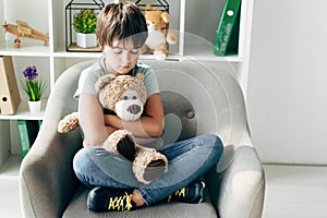 Kid with dyslexia holding teddy bear and sitting