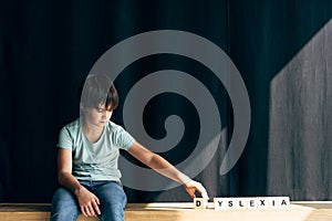 Kid with dyslexia playing with wooden cubes