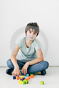 Kid with dyslexia sitting on floor with building blocks