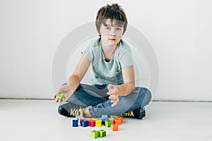 Kid with dyslexia sitting on floor with building blocks