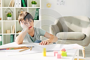 Kid with dyslexia sitting at table and looking away