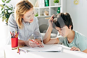 Kid with dyslexia and smiling child psychologist sitting at table