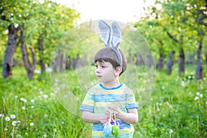 Kid on Easter egg hunt in blooming spring garden. boy searching for colorful eggs in flower meadow