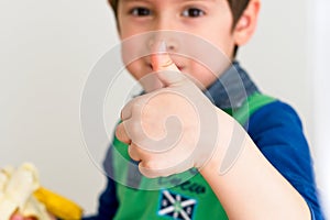 Kid eating a banana and with his thumb up showing he`s fine