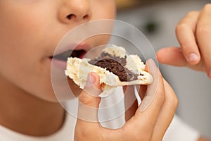 Kid eating bread with nut chocolate butter