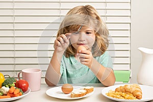 Kid eating egg. Child eats organic food. Healthy vegetables with vitamins. Proper kids nutrition concept.