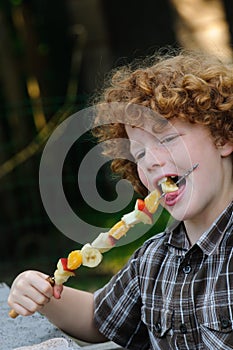 Kid eating fruit skewer