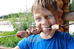 Kid eating pork neck kebab with ketchup