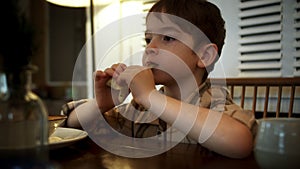 Kid eats fast food close-up. Child greedily with pleasure bites a big burger in lifestyle the kitchen at home. little