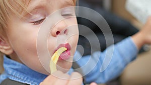 The kid eats a fried potato at a fast food restaurant closeup