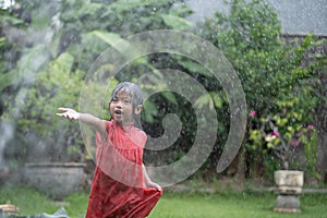 Kid enjoying playing with water splash in garden