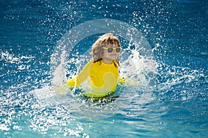 Kid enjoying summer holiday, swiming in pool. Kid having fun on summer holidays at pool. Happy kids playing on pool