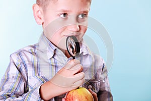 Kid examine apple with magnifying glass.