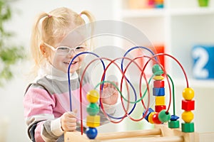 Kid in eyeglases playing colorful toy in home photo