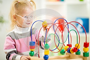Kid in eyeglases playing colorful toy in home photo