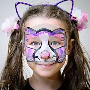 Kid with face painting of kitty, cute little girl with painted mask