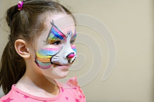 Kid with face painting of kitty, cute little girl with painted mask on face of rainbow cat