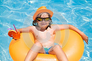 Kid floating in pool. Child relaxing in pool, drink summer cocktail. Outdoor summer activity for children. Happy child