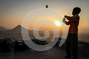 Kid flying his kite at sunset at the Pap Mochani Gayatri Temple, Pushkar, Rajasthan, India