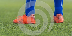 Kid footballer feet closed up on green grass field for youth soccer training concept