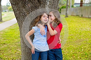 Kid friend girls whispering ear playing in a park tree