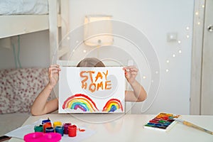 Kid girl drew rainbow and poster stay home. photo