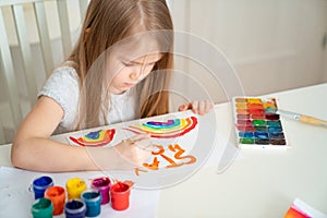 Kid girl drew rainbow and poster stay home. photo