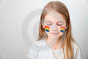 Kid girl painted cheeks a rainbow. stay home. photo