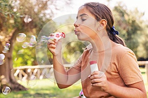 Kid Girl blowing soap bubbles in a park in summer