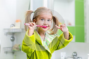 Kid girl brushing teeth in bathroom
