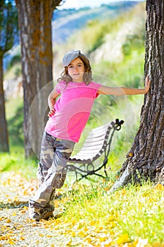 Kid girl with camouflage pants and cap in park bench outdoor