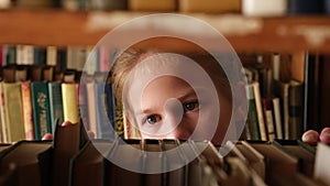 Kid girl choose books on shelf of old library. Schoolgirl selecting literature for reading