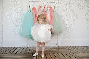 Kid girl in dress near hanger with festive clothes photo