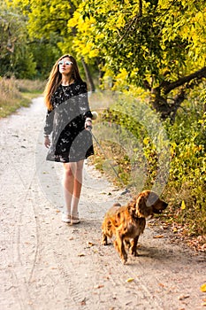 Kid girl in dress running with the dog in the countryside at susnset