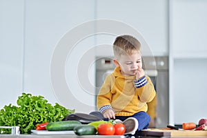 Kid girl eating healthy vegetables at kitchen