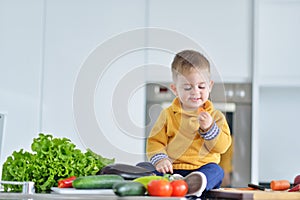 Kid girl eating healthy vegetables at kitchen