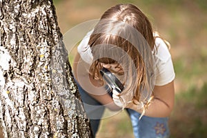 Kid girl explores bark of tree magnifying glass