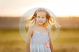 Kid girl grey dress stand on sloping wheat field