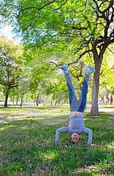 Kid girl handstands upside down in the park