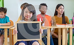 Kid girl holding blank blackboard with diversity friends and tea