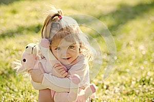 Kid girl hug soft horse toy on sunny day