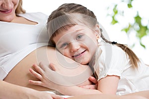 Kid girl hugging pregnant mother's stomach