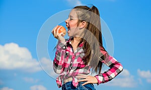 Kid girl with long hair eat apple blue sky background. Healthy nutrition concept. Child eat ripe apple fall harvest