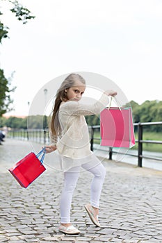 Kid girl with long hair fond of shopping. Fashionista girl shopping with pink bags. Shopping concept. Girl likes to buy